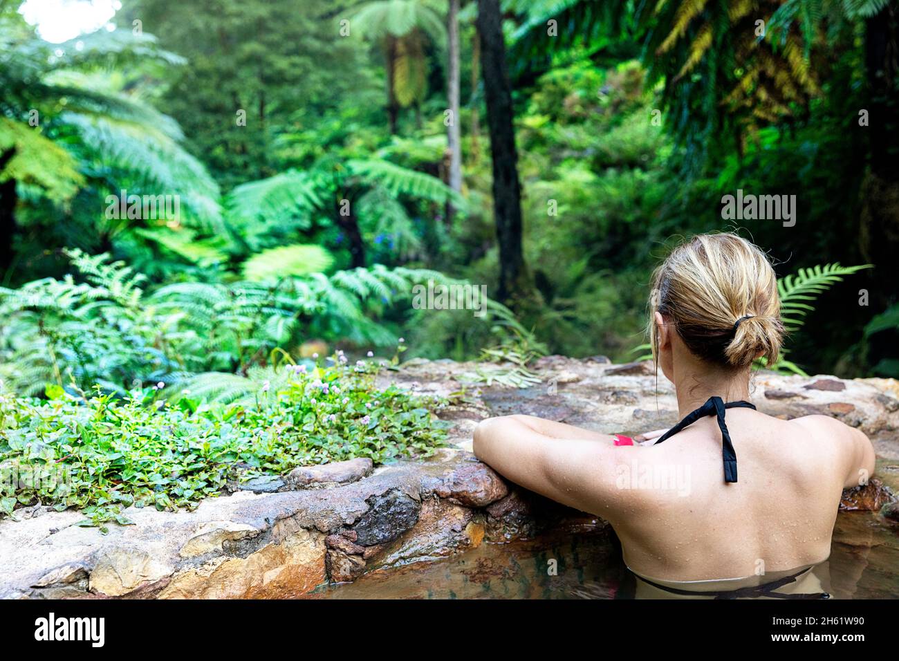 Vue arrière d'une femme se baignant dans les piscines thermales de Caldeira Velha, Sao Miguel, Açores, Portugal Banque D'Images