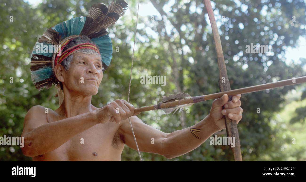 Indien de la tribu Pataxó, avec une plume de headaddress et d'arc et de flèche. Indien brésilien âgé regardant à droite. Banque D'Images