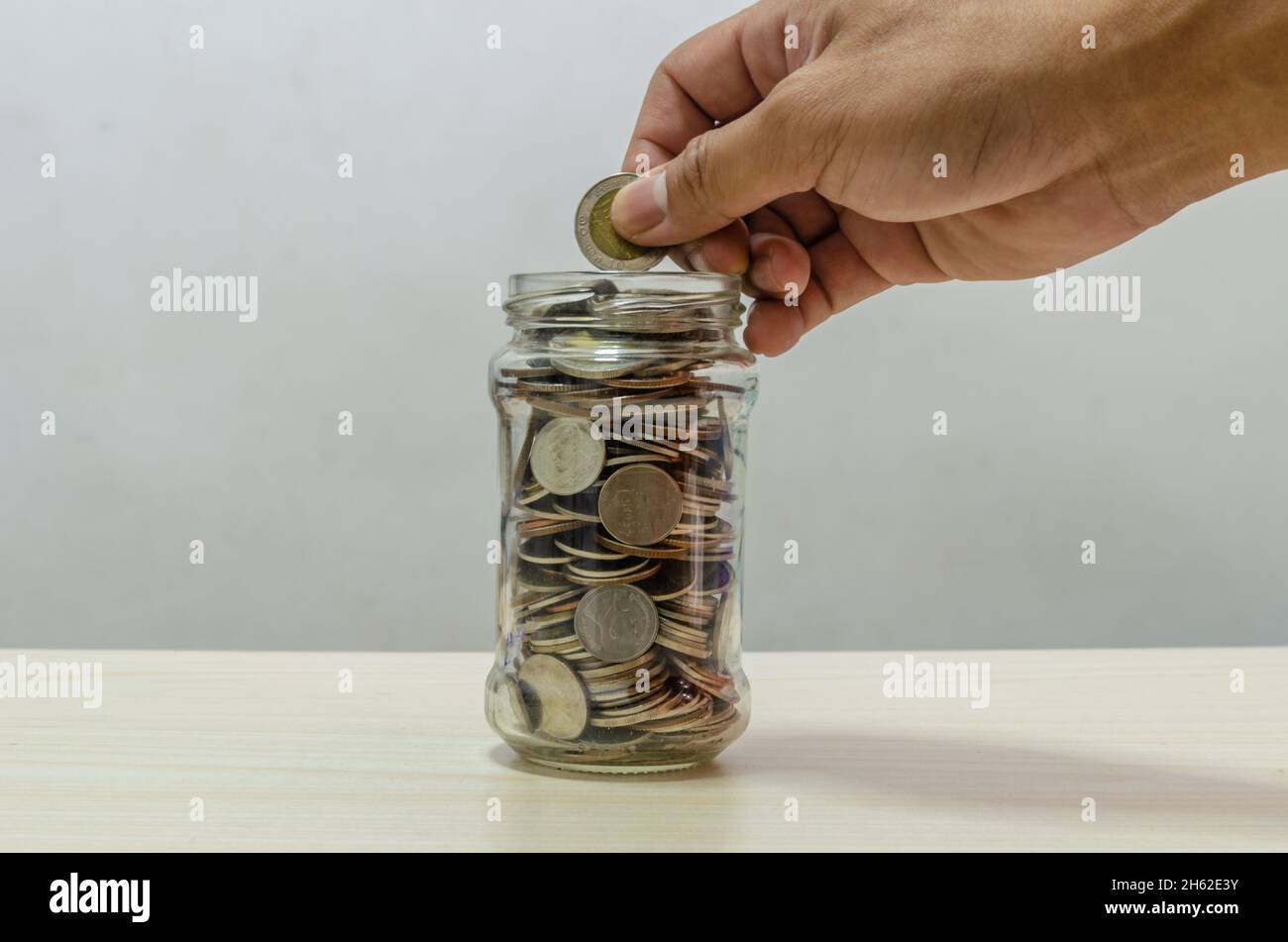 Main tenant une pièce de monnaie dans un pot en verre. Concept d'économie d'argent. Planification financière et d'investissement pour l'avenir. Banque D'Images