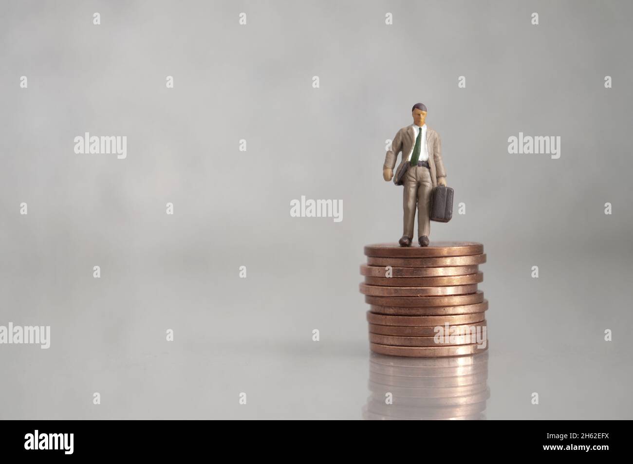 Homme d'affaires miniature debout sur un tas de pièces Banque D'Images