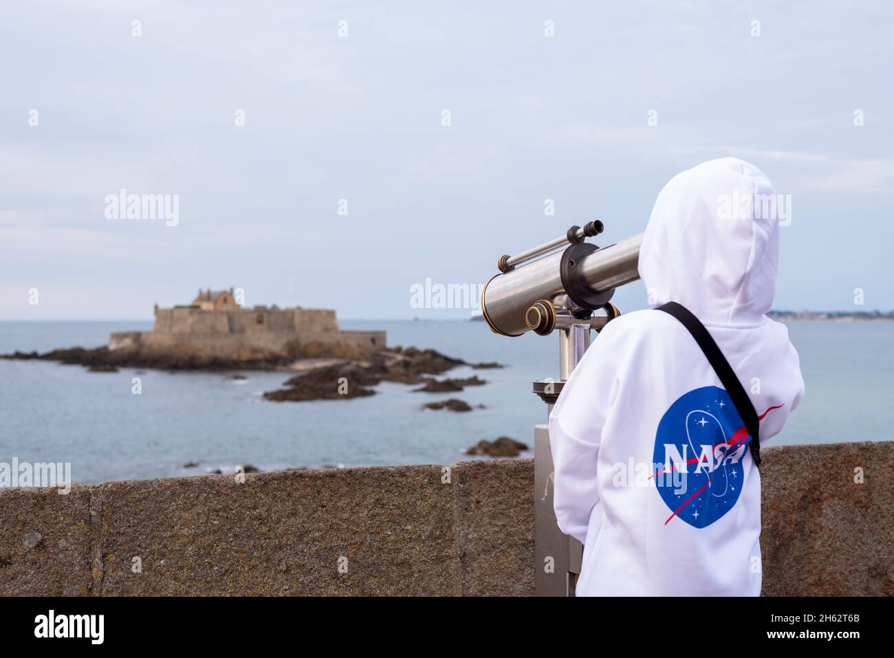 france,bretagne,ille et vilaine,saint malo,boy regarde à travers un télescope à l'île marémotrice de petit-bé avec le fort national, côte atlantique Banque D'Images