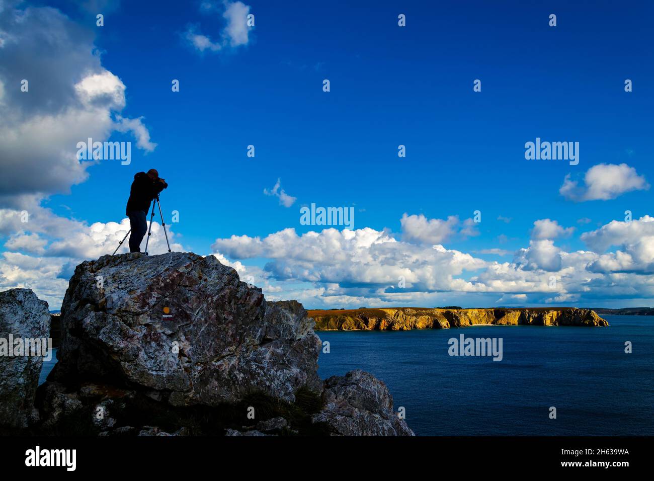 Photographe de plein air debout sur un rocher et prenant des photos du paysage à couper le souffle de la Bretagne près de la Pointe de Penhir Banque D'Images