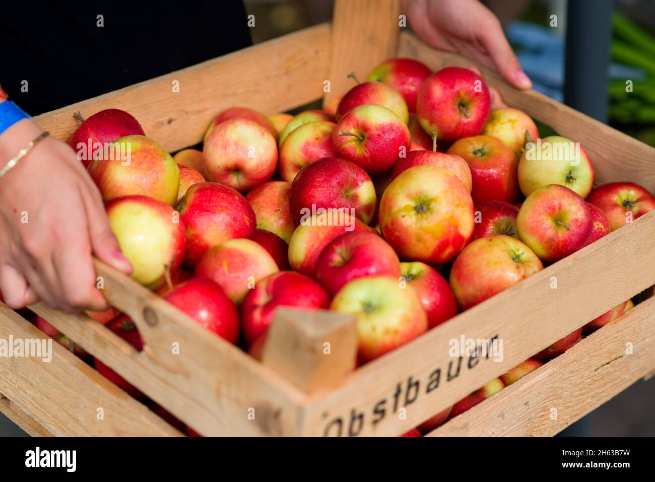 la femme porte une caisse de fruits avec des pommes Banque D'Images