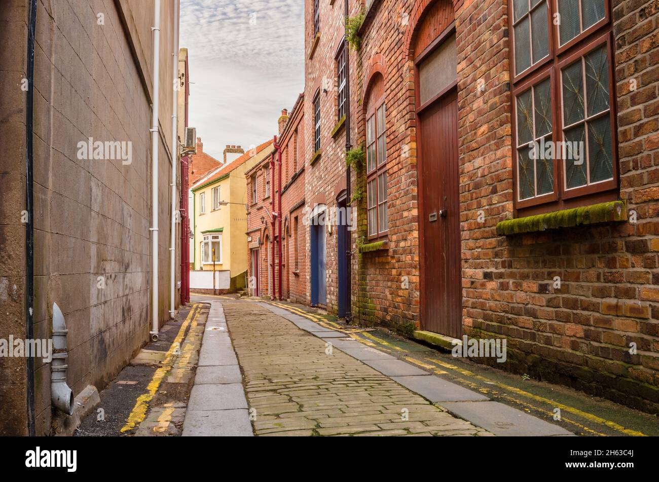 Ruelle en pierre étroite déserte bordée de vieux bâtiments en briques dans un centre-ville Banque D'Images