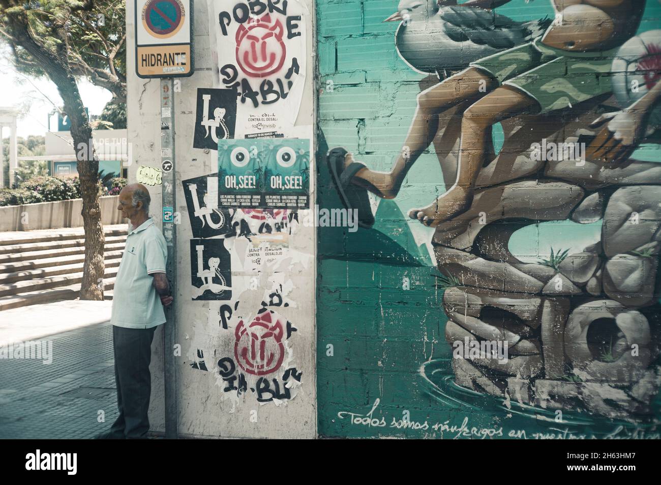 un gars à un coin dans la ville de malaga, espagne - à côté d'un art mural / grafitti Banque D'Images