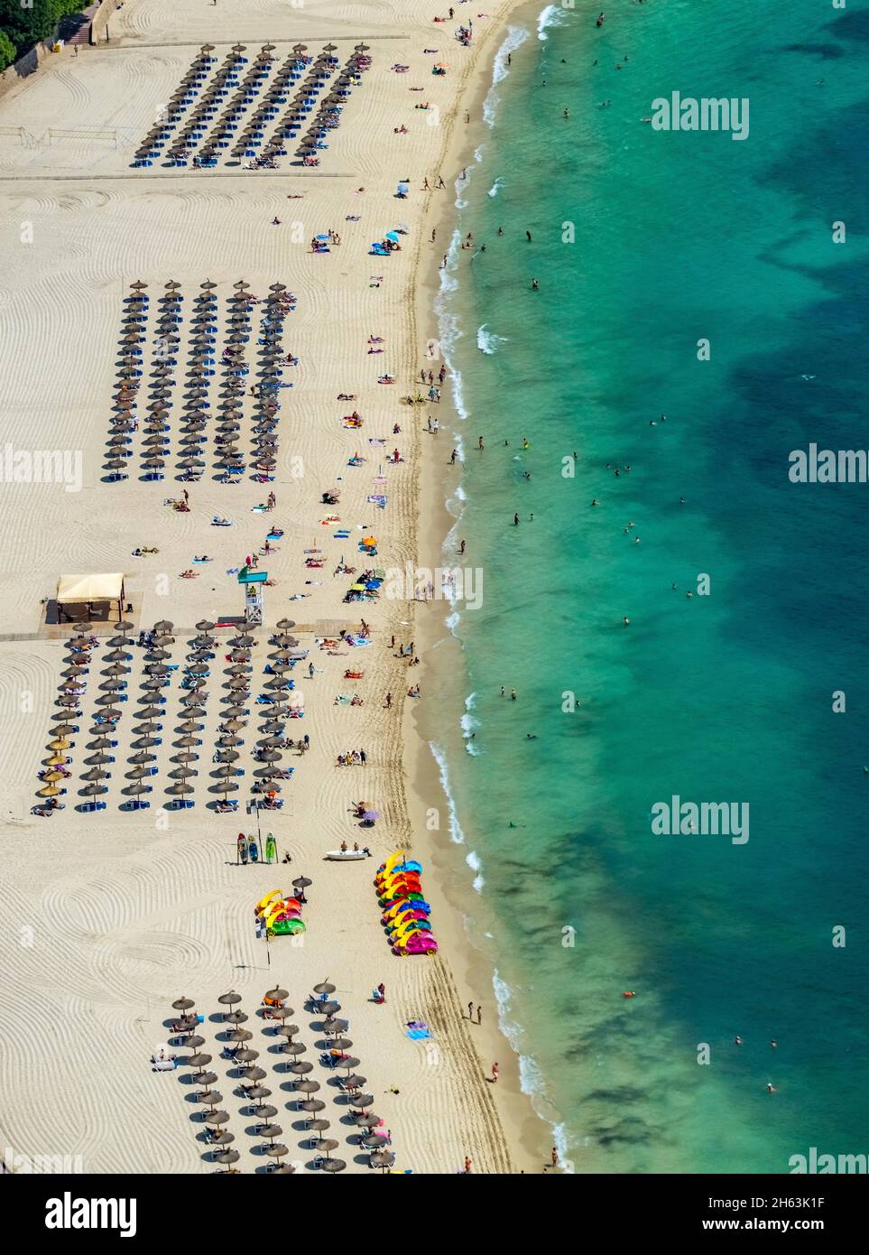 vue aérienne, plage de sable playa de palmanova, vie de plage et bains de soleil avec parasols en paille dans les rangées, bateaux d'eau colorés pour enfants avec toboggan, palmanova, calvià, majorque, iles baléares, espagne Banque D'Images