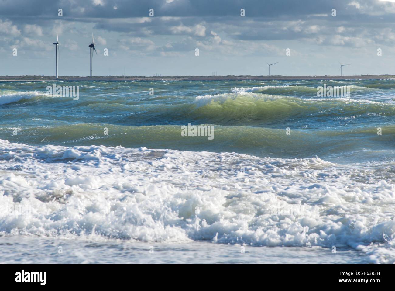 surf modéré avec un ciel partiellement nuageux sur la plage de la mer du nord près de neeltje jans. en arrière-plan quelques éoliennes. Banque D'Images