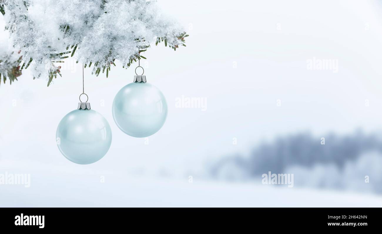 boules de noël en verre sur une branche de pin sur un fond enneigé flou Banque D'Images