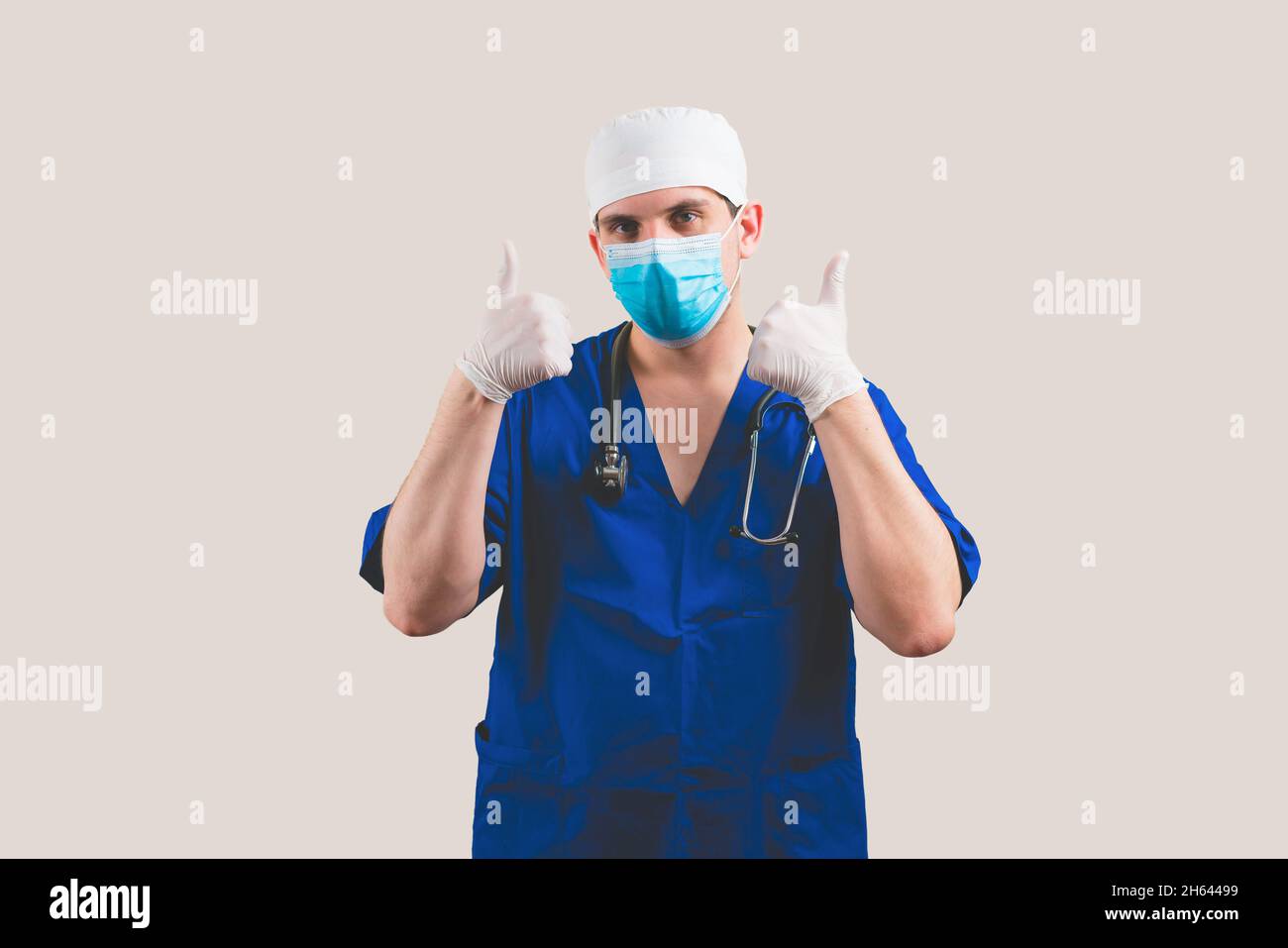 Jeune médecin avec pouces vers le haut dans bleu combinaison de chirurgien et des lunettes avec stéthoscope sur le fond jaune isolé Banque D'Images