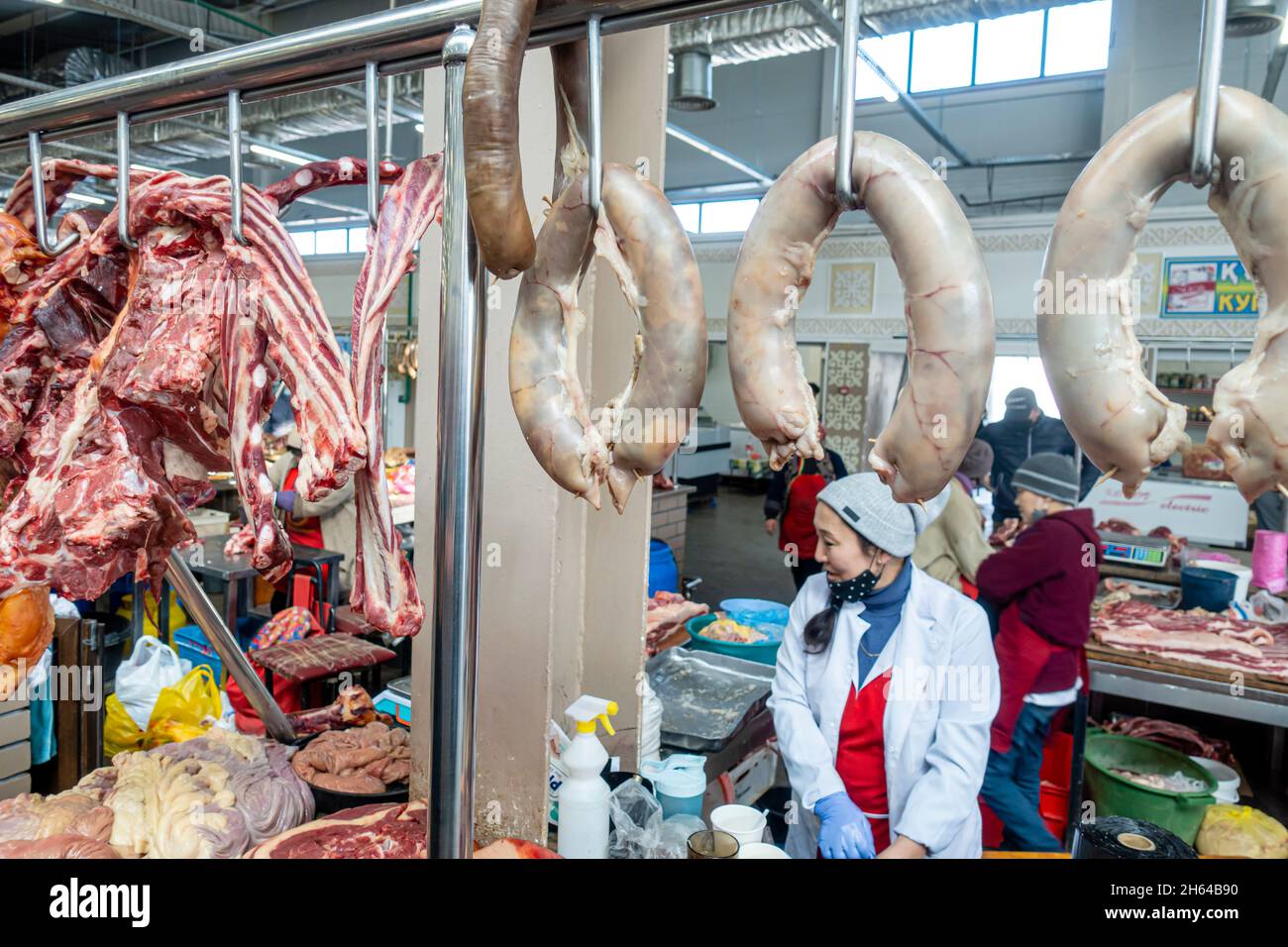 Une femme kazakh au comptoir vendant de la viande de cheval suspendue, qazy, saucisse de cheval.Marché de la viande à Altyn Orda, Almaty, Kazakhstan Banque D'Images