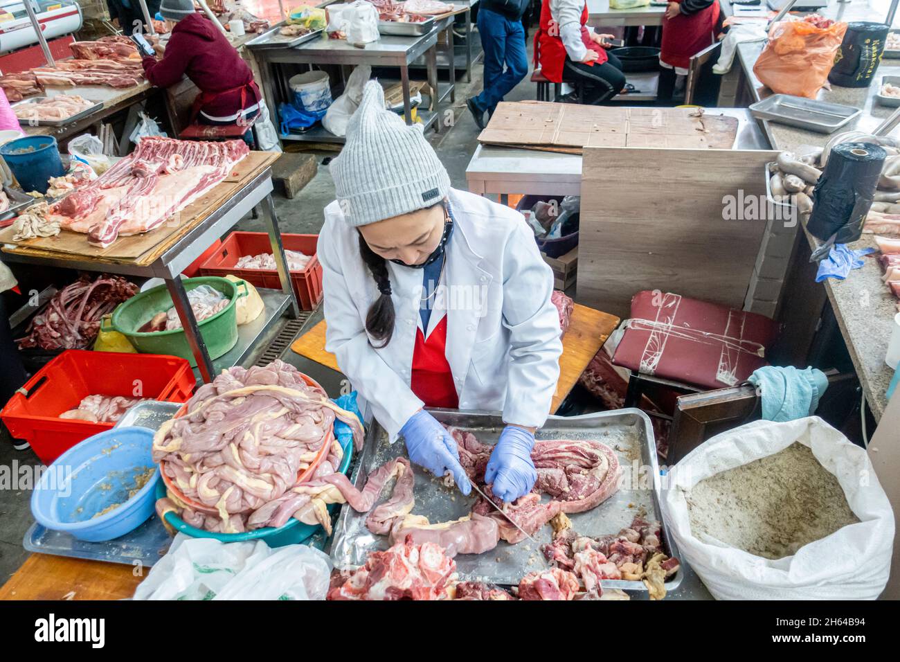 Une femme kazakh coupe de la viande de cheval pour préparer du qazy, saucisse de cheval dans le marché de la viande Altyn Orda, Almaty, Kazakhstan Banque D'Images