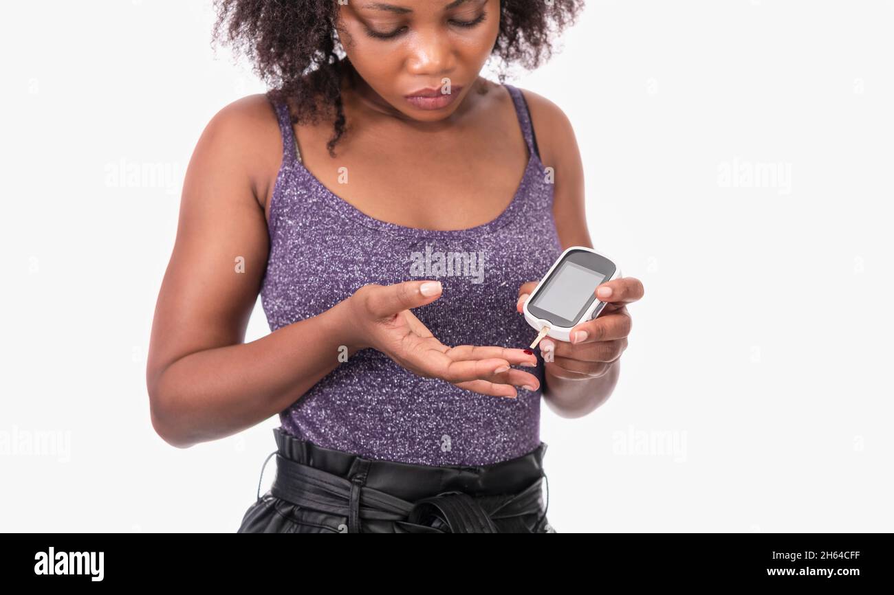Femme utilisant un glucomètre numérique sur fond blanc Banque D'Images