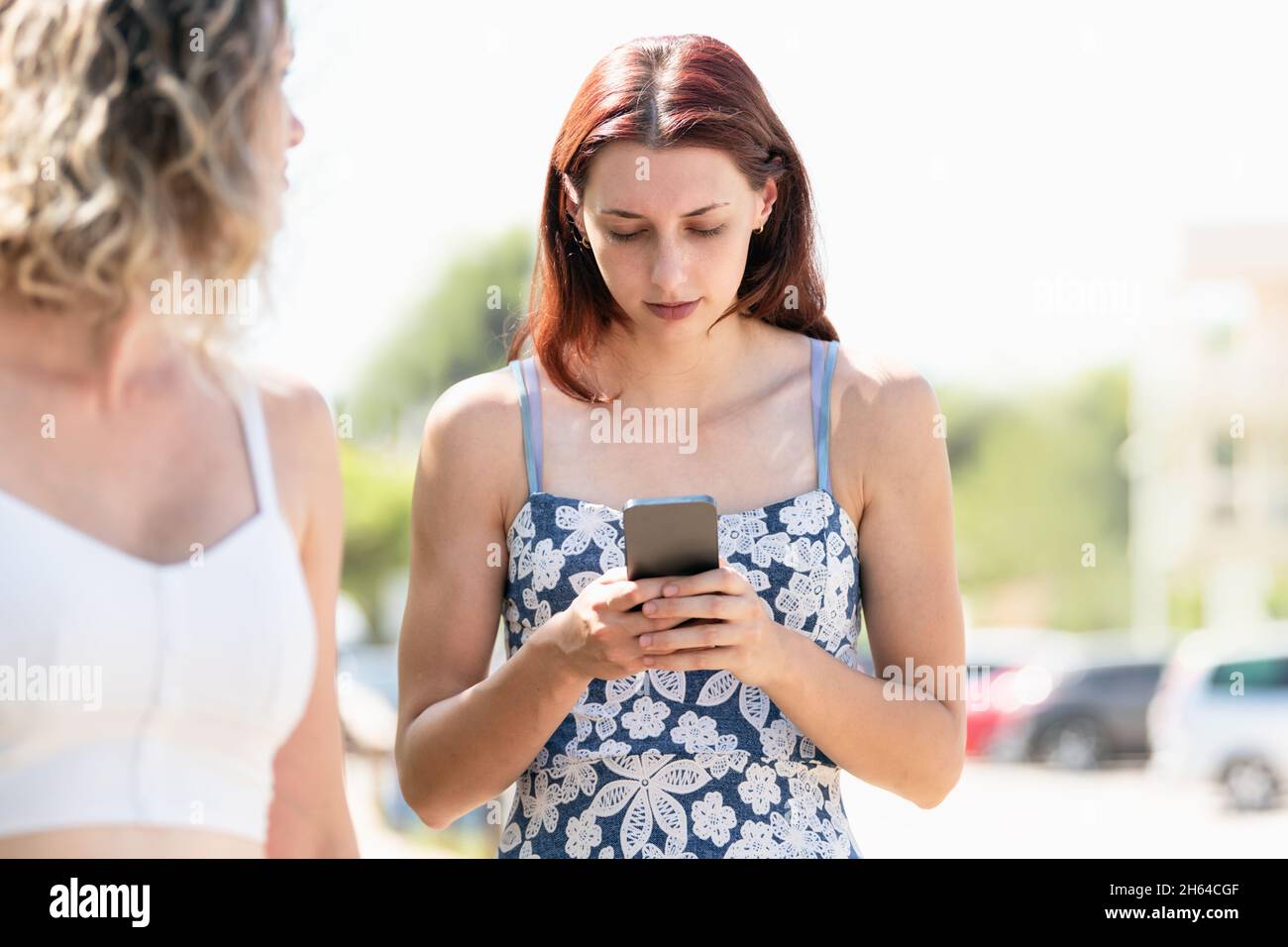 Femme concentrée utilisant un mobile tout en se tenant à côté d'un ami Banque D'Images