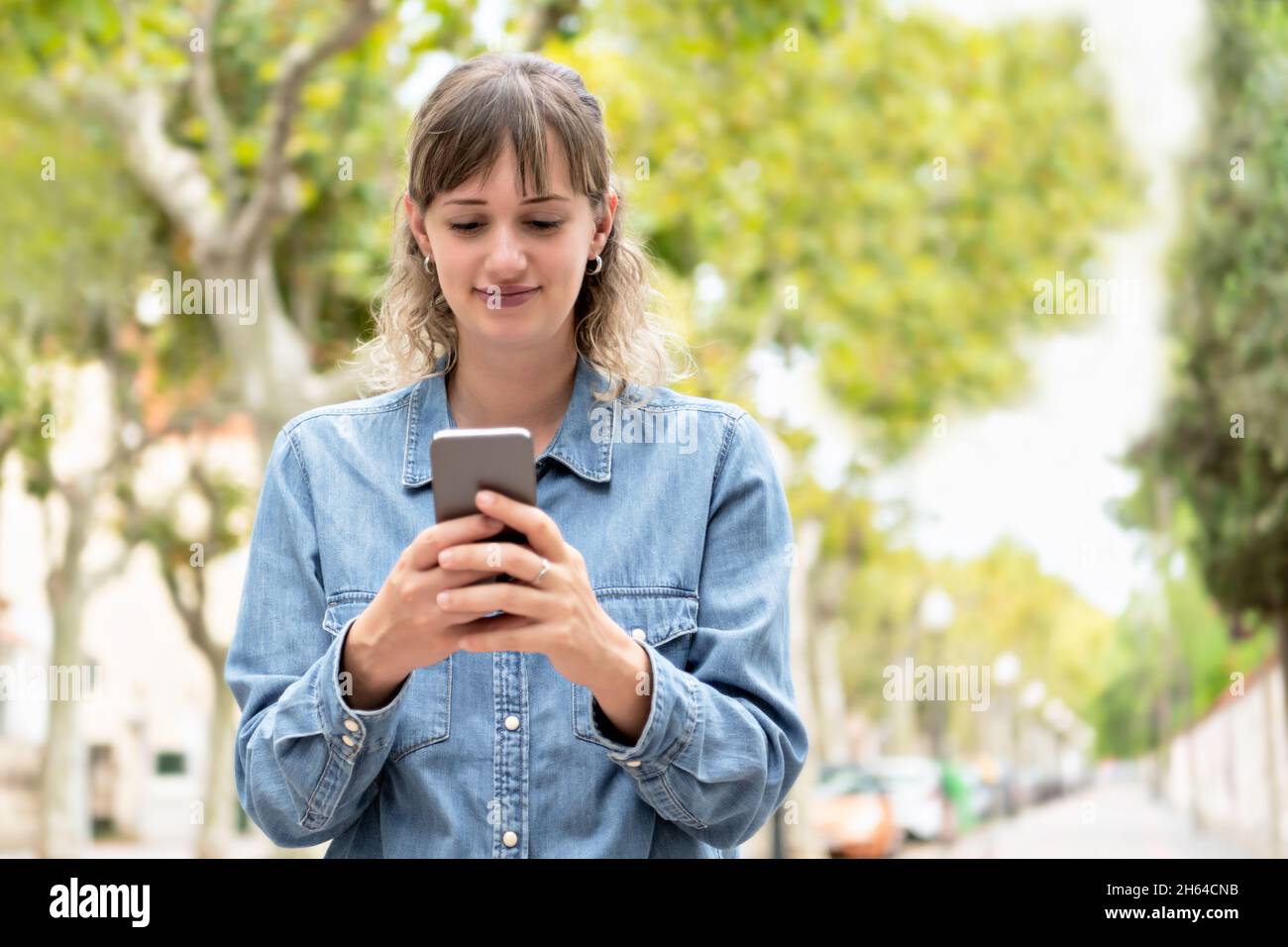 Une femme utilisant son téléphone avec les deux mains à l'extérieur Banque D'Images