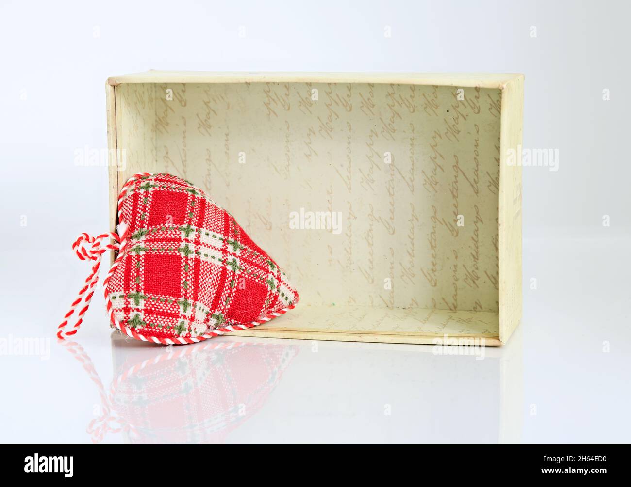 Un coeur en textile avec une petite boîte en carton sur fond blanc Banque D'Images