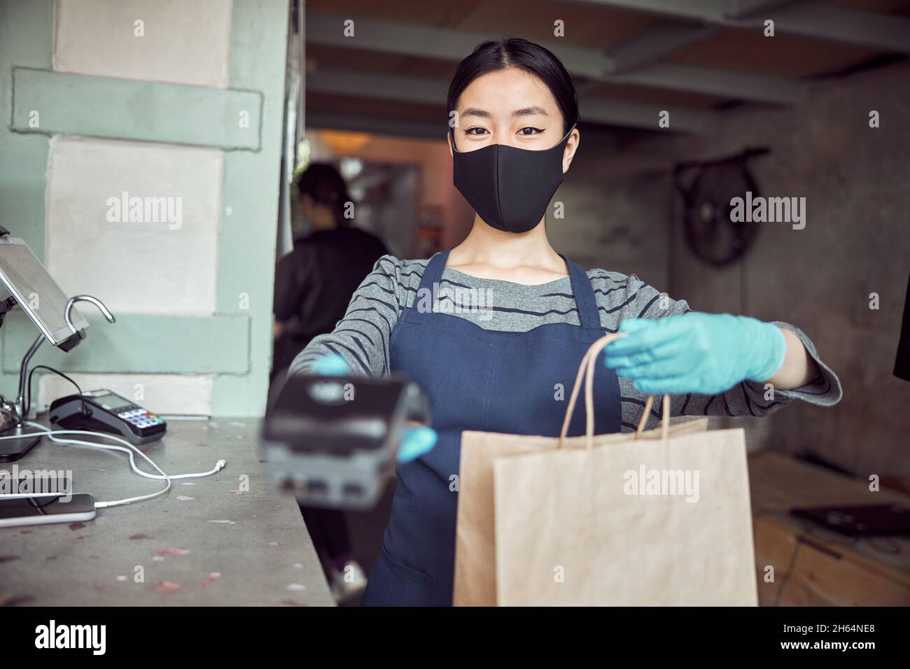 Portrait d'une serveuse de café avec machine à cartes derrière le comptoir Banque D'Images
