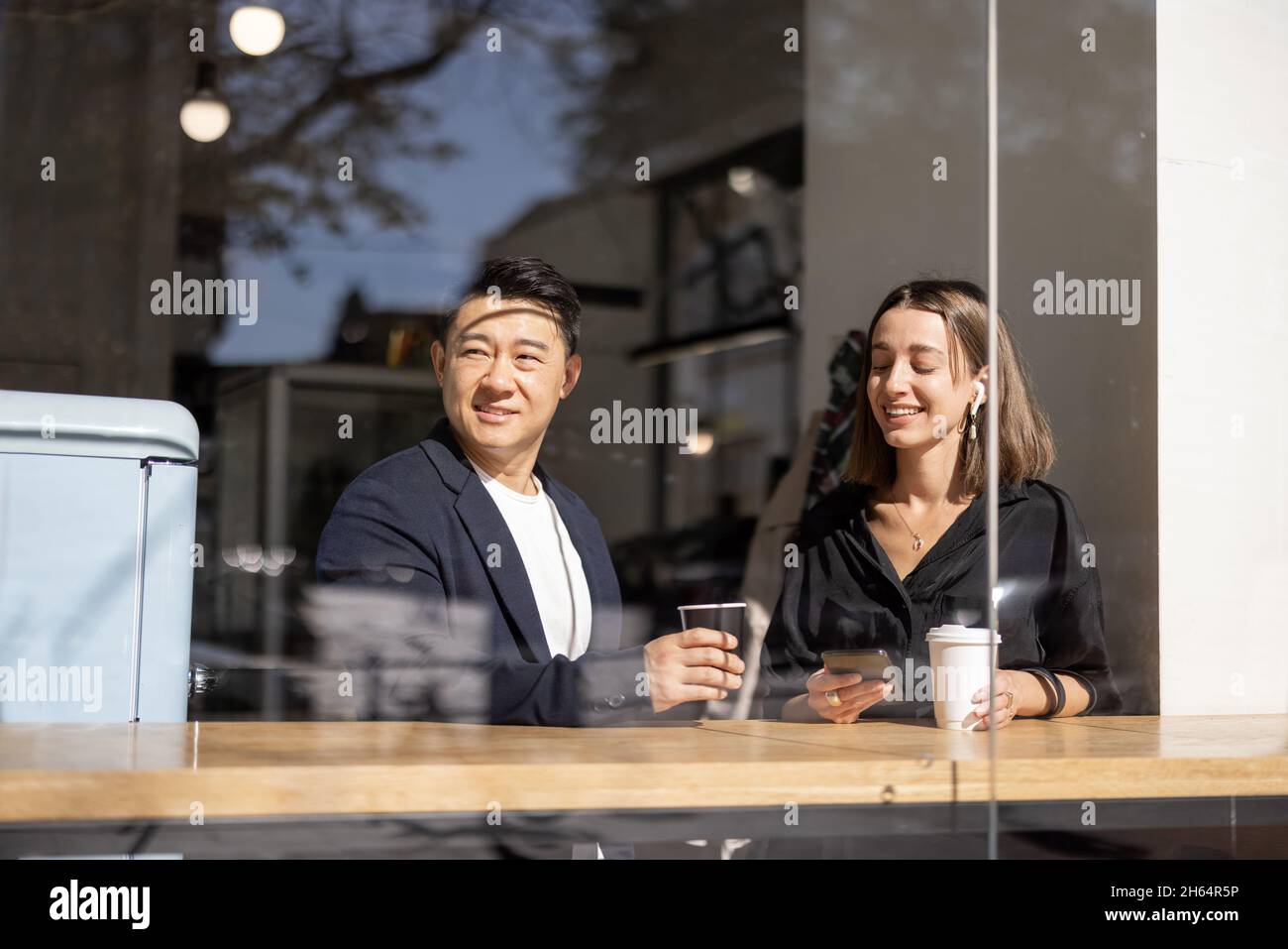 Un couple multiracial boit du café à table dans le café Banque D'Images