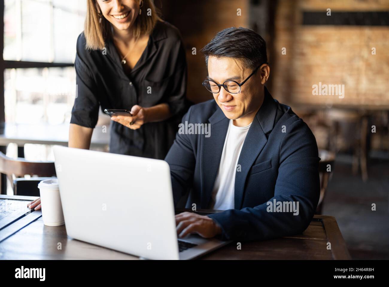 Homme montrer quelque chose sur ordinateur portable à la femme dans le café Banque D'Images