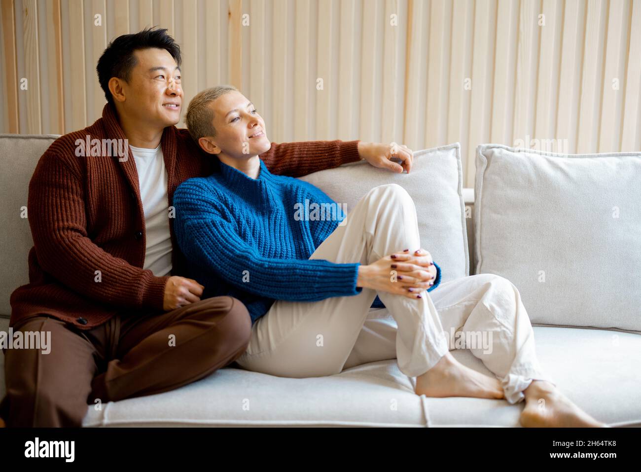 Couple multiracial s'asseoir et se reposer sur le canapé à la maison Banque D'Images