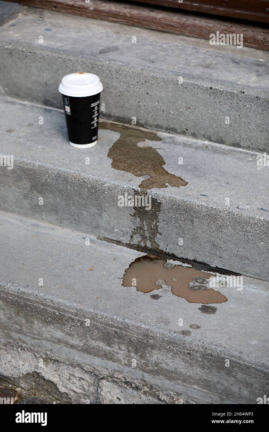 Tasse de café en papier et café renversé sur les escaliers en béton Banque D'Images