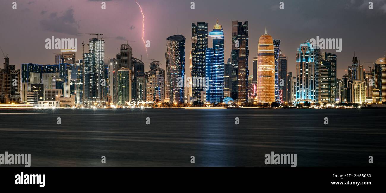 Doha Qatar skyline at night montrant les lumières des gratte-ciel reflétées dans le golfe Arabe Banque D'Images