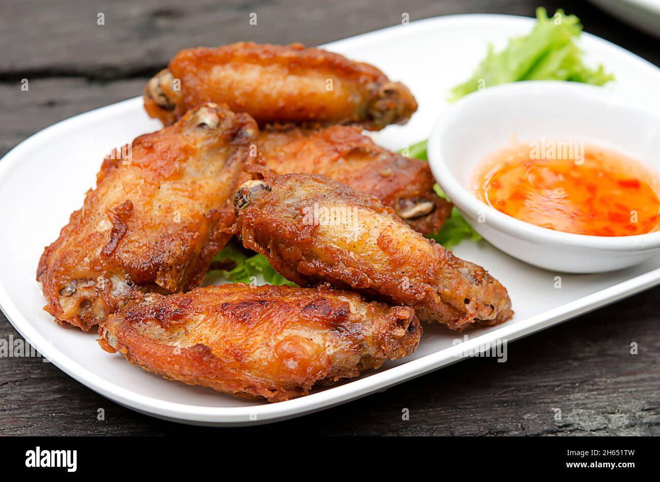 Des ailes de poulet sur le plat blanc fond bois. Banque D'Images