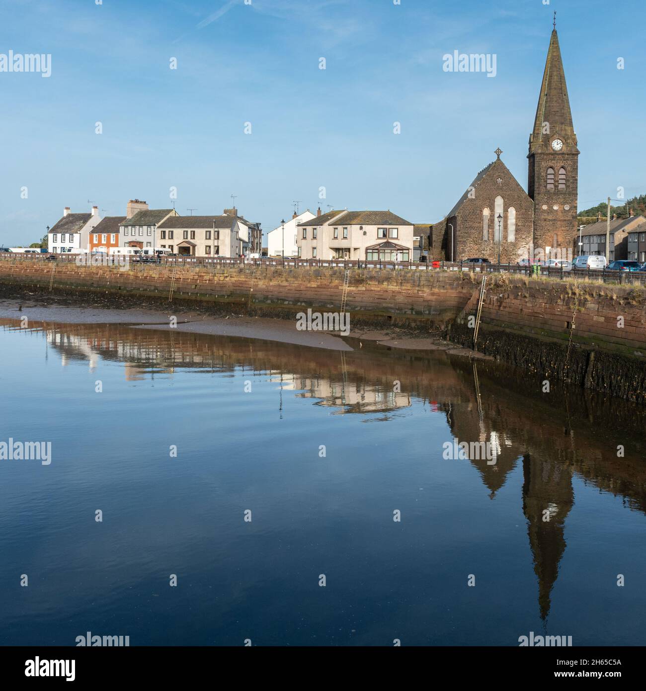La ville côtière et le port de pêche de Maryport, côte de West Cumbria, Angleterre, Royaume-Uni, avec des chalets et l'église se reflète dans le port Banque D'Images