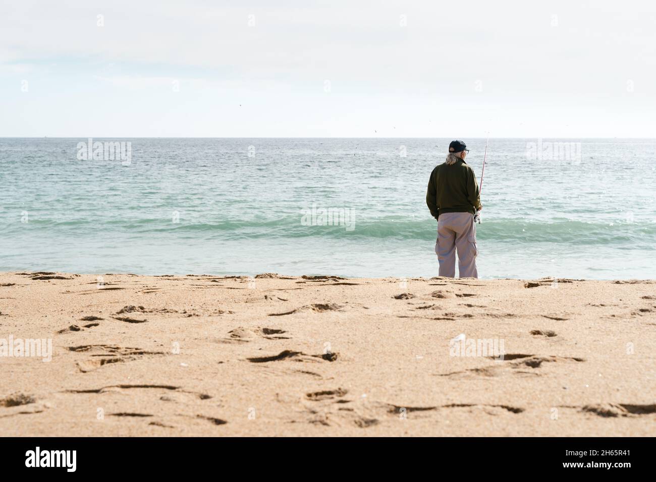 Homme solitaire senior pêche sur la plage.Personne aînée profitant de la retraite par le concept de la mer Banque D'Images