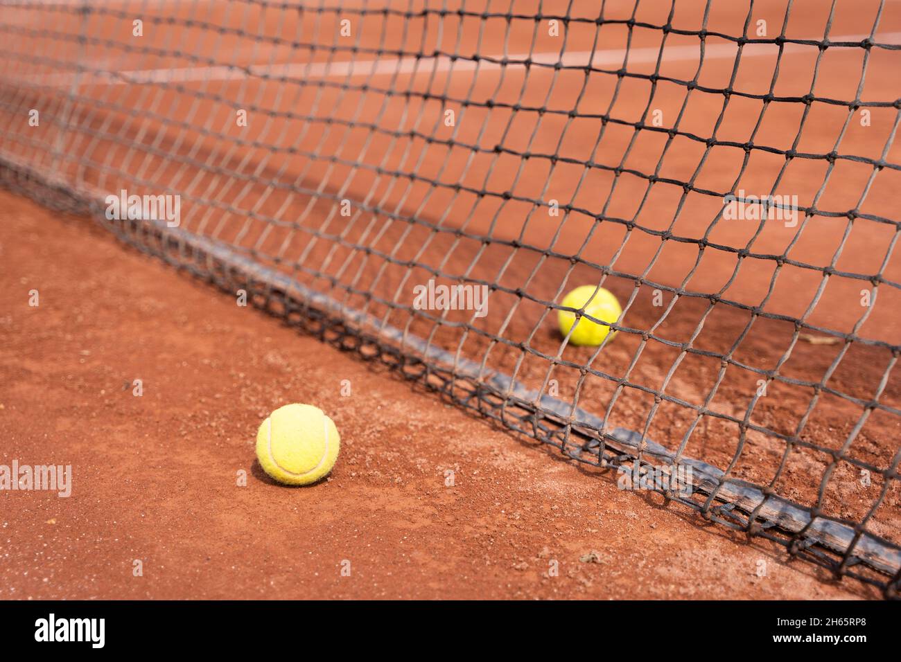 Deux balles de tennis séparées par un filet sur un terrain en terre battue.Concept d'entraînement de tournoi sportif Banque D'Images