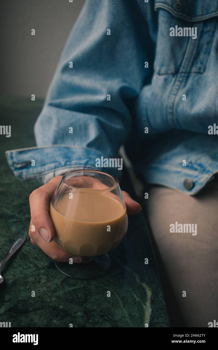 Modèle jeune à la mode avec une tasse de café latte en verre et une cuillère Banque D'Images