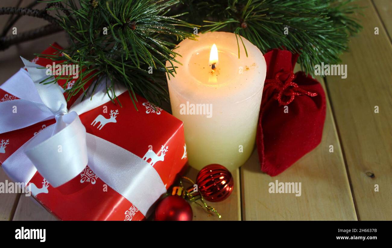 Bougie allumée sur un plancher en bois sur le fond de branches de sapin.Le sac cadeau rouge et la boîte cadeau du nouvel an sont décorés avec soin d'un W Banque D'Images