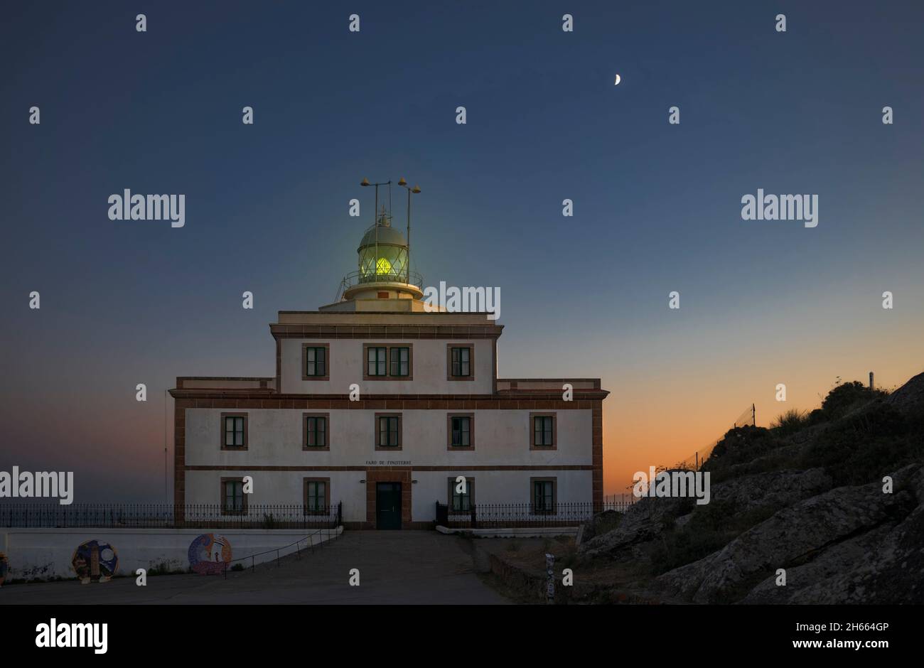 Feu vert au phare de Fisterra pendant la Lune du croissant, Galice, Espagne Banque D'Images