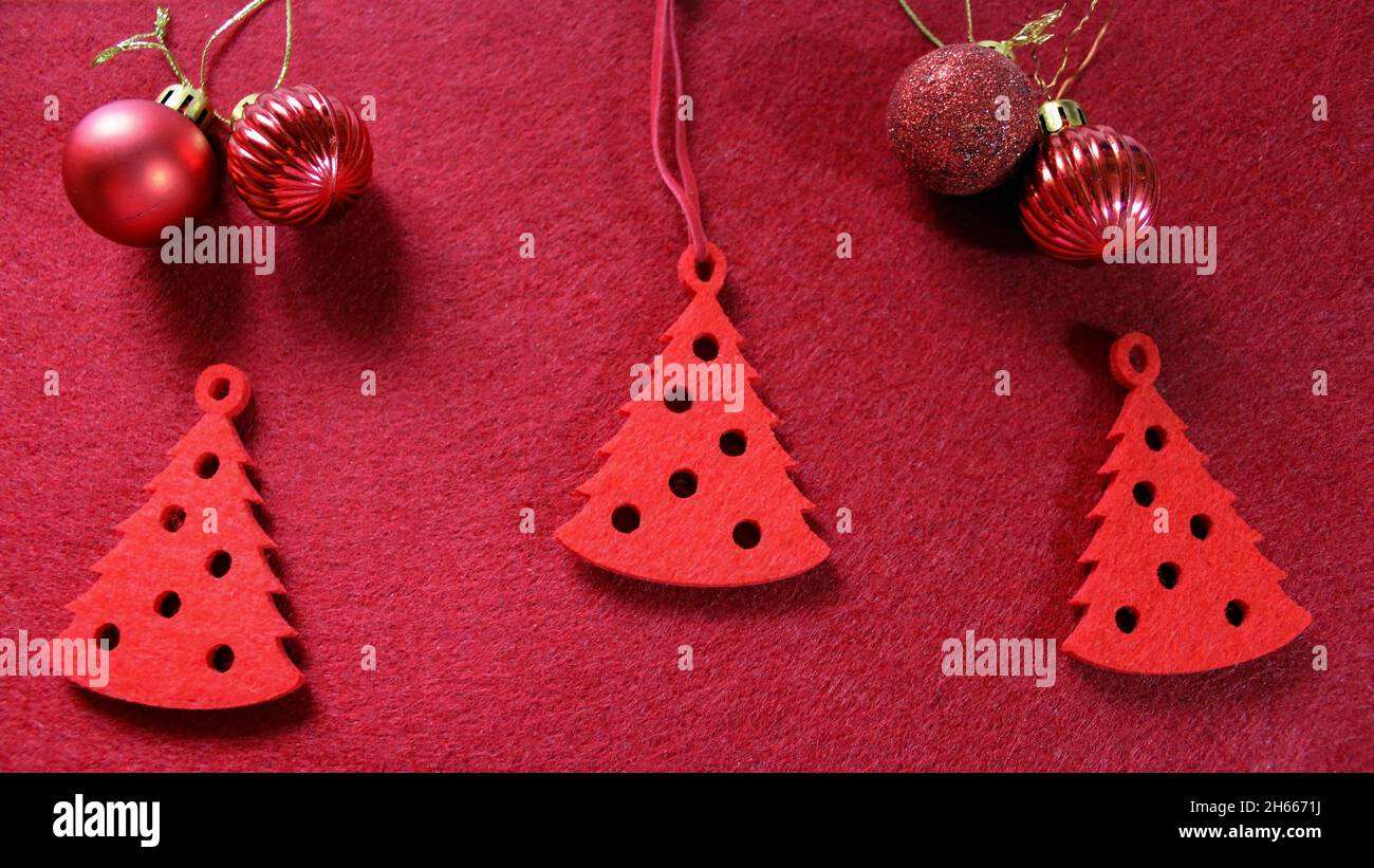 Jouet arbre de Noël en feutre rouge en forme d'arbre de Noël.Trois arbres de Noël sur fond rouge avec des boules de Noël.Nouvelle année. Banque D'Images