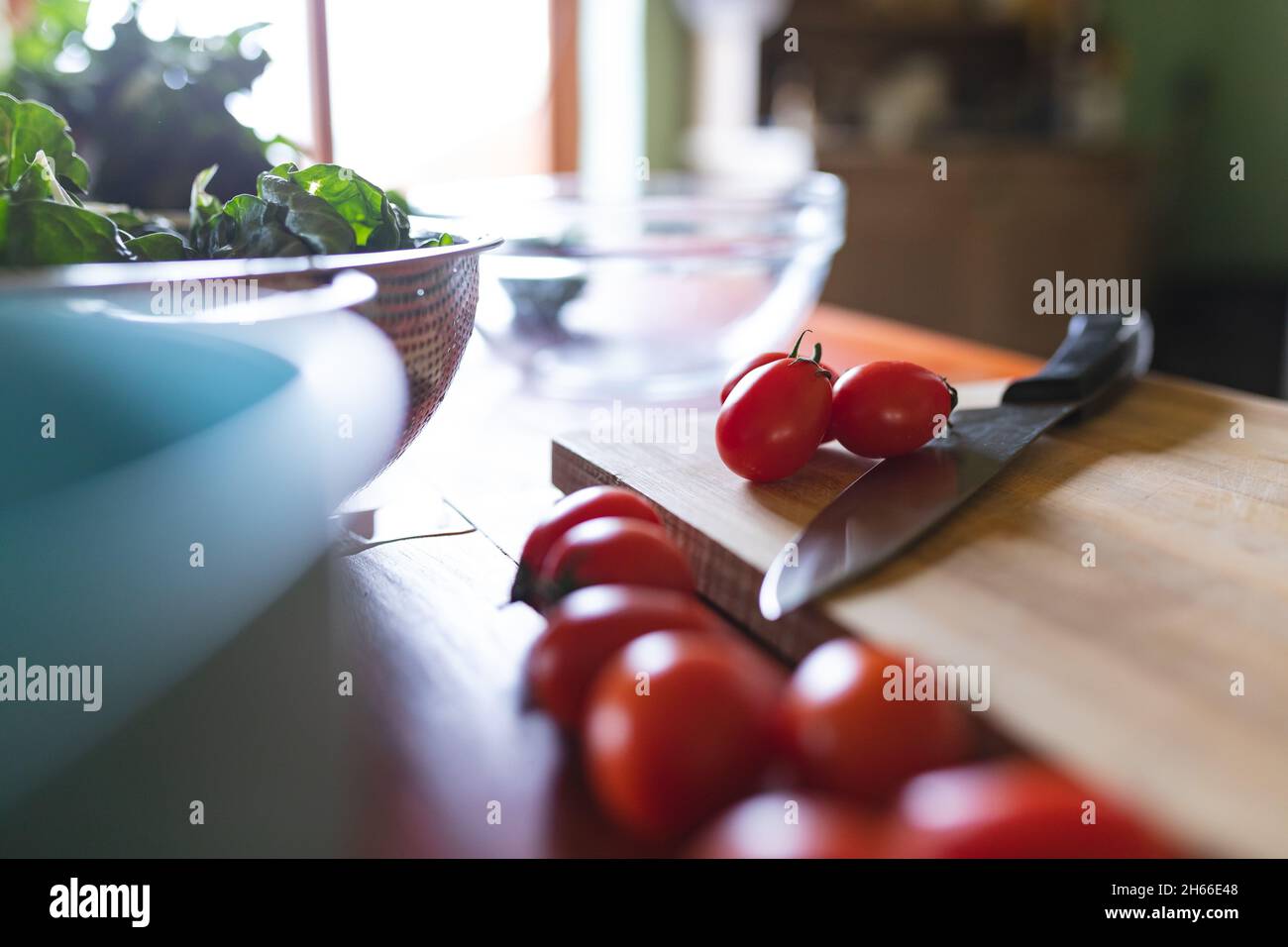 Gros plan de tomates cerises rouges fraîches avec couteau sur planche à découper en bois dans la cuisine Banque D'Images