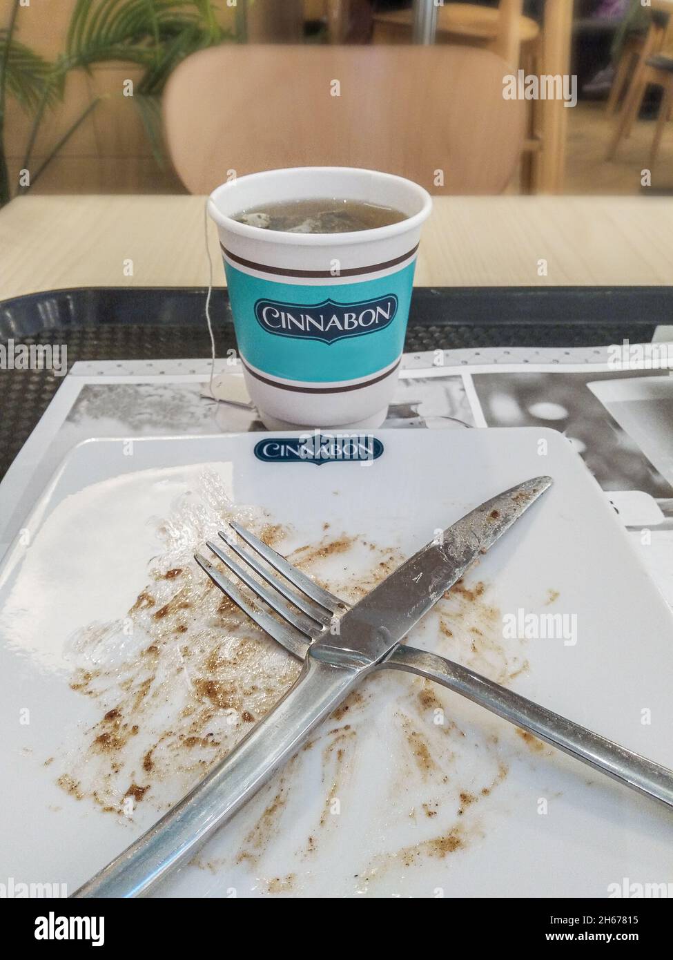 Saint-Pétersbourg, Russie - 21 juin 2021.Une tasse jetable avec le thé et le gâteau cinnabon a commencé et fini, fourchette et couteau, sur la table Banque D'Images