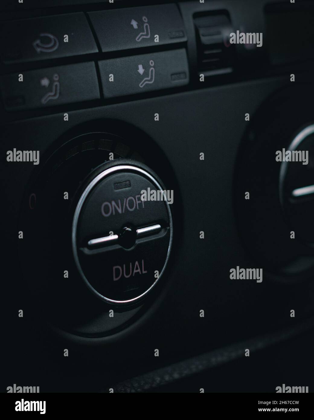 Photo verticale des boutons noirs du panneau de commande de climatisation d'une voiture sur fond noir Banque D'Images