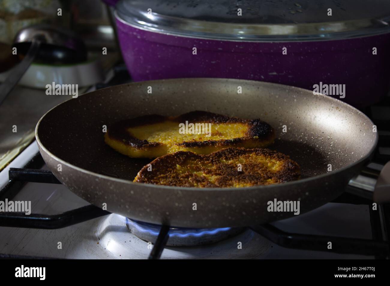 Homme cuisant à la main du schnitzel de poulet dans une casserole de granit sur feu bleu. Banque D'Images