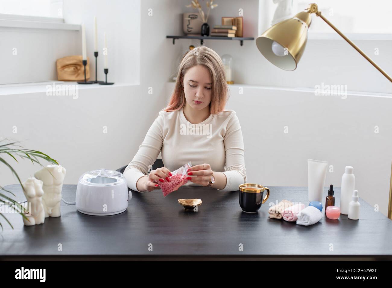 Jeune femme qui fait de la cire, l'enlèvement de cheveux, le sharing.Petite entreprise, procédure d'enseignement de concept. Banque D'Images