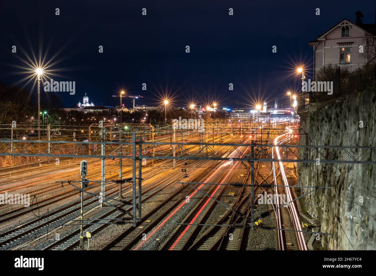 Helsinki / Finlande - 13 NOVEMBRE 2021 : en contournant les trains qui parcourent des pistes de lumière sur les voies ferrées, avec une belle vue d'horizon de la ville en arrière-plan. Banque D'Images