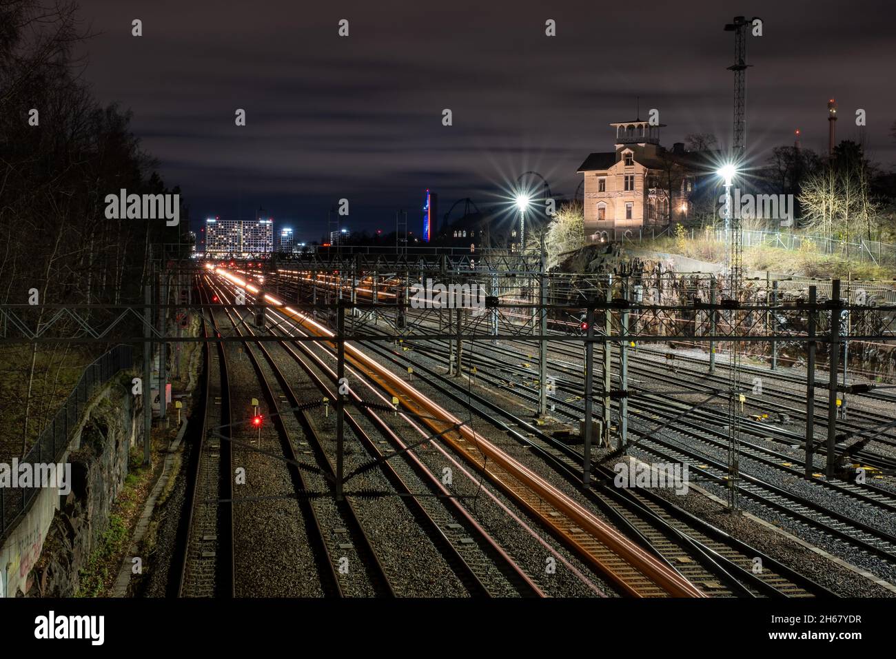 Helsinki / Finlande - 13 NOVEMBRE 2021 : en contournant les trains qui parcourent des pistes de lumière sur les voies ferrées, avec une belle vue d'horizon de la ville en arrière-plan. Banque D'Images