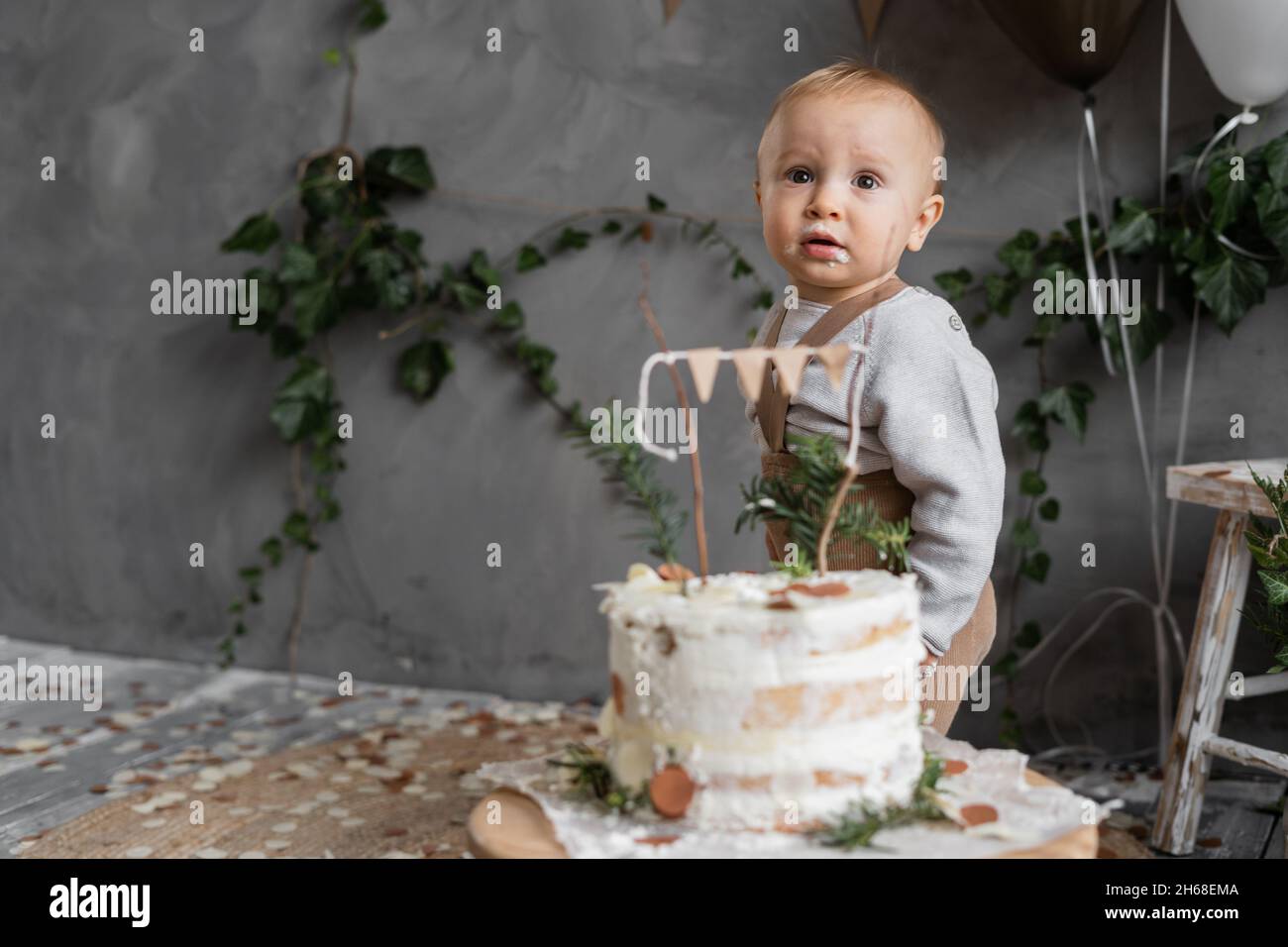 Portrait d'un petit garçon à son premier anniversaire, gâteau sur la table près de l'enfant, fond gris, endroit pour le texte, couleurs naturelles de la décoration.Un an Banque D'Images