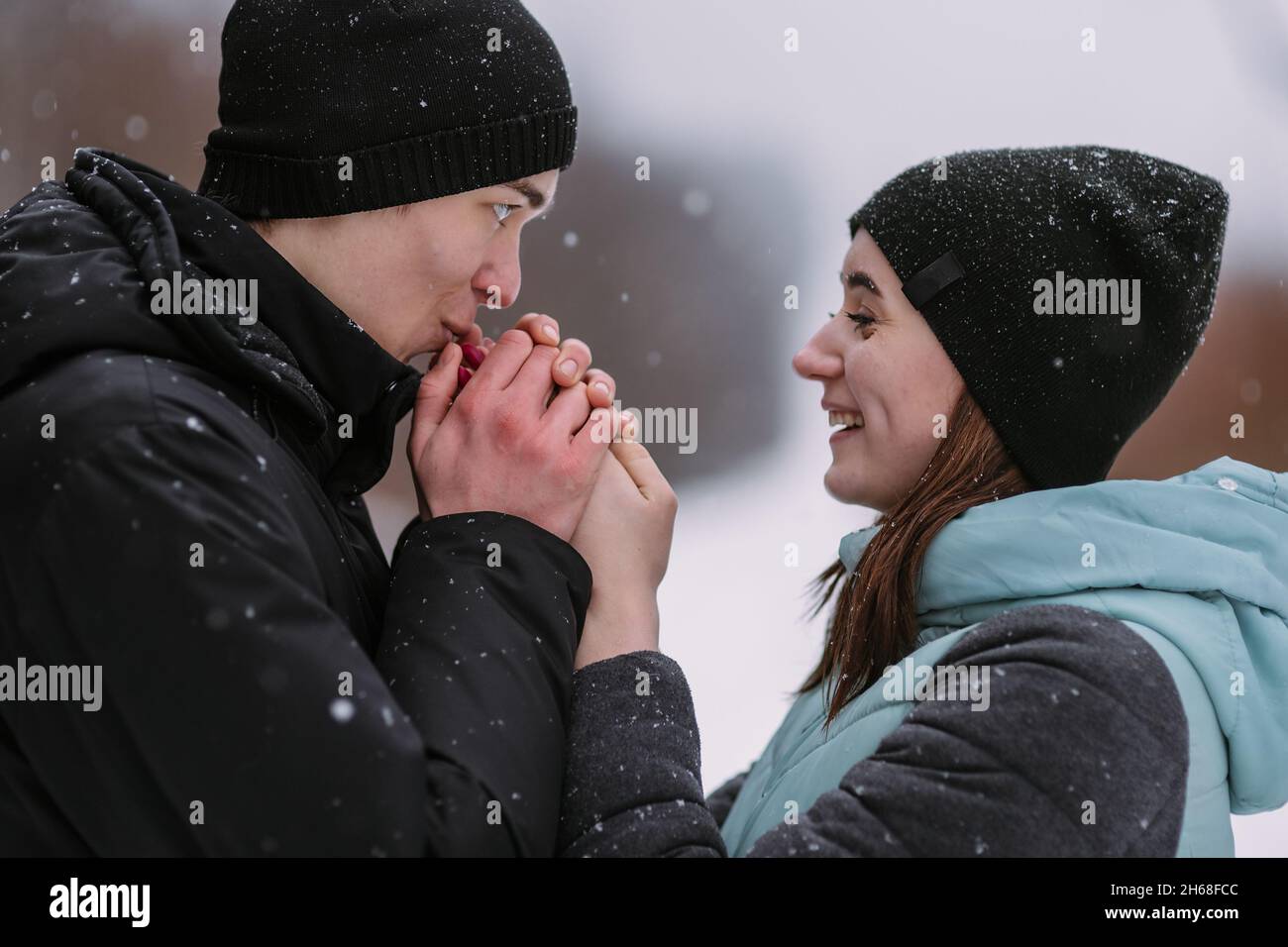 Portrait de couple d'adolescents en forêt d'hiver.Petit ami réchauffant les mains de la petite amie Banque D'Images