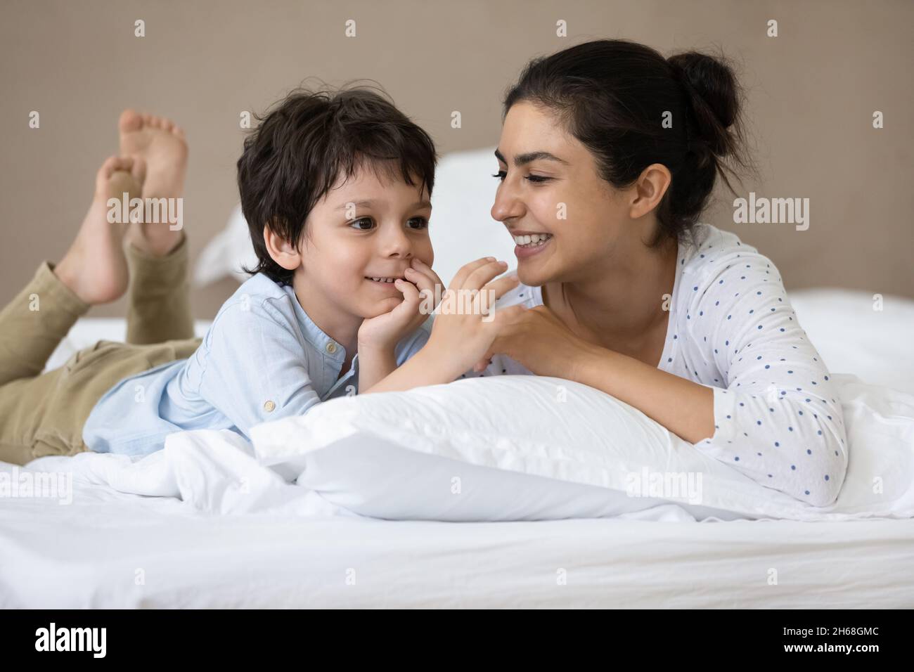 Un petit garçon indien heureux et une maman gaie au lit Banque D'Images