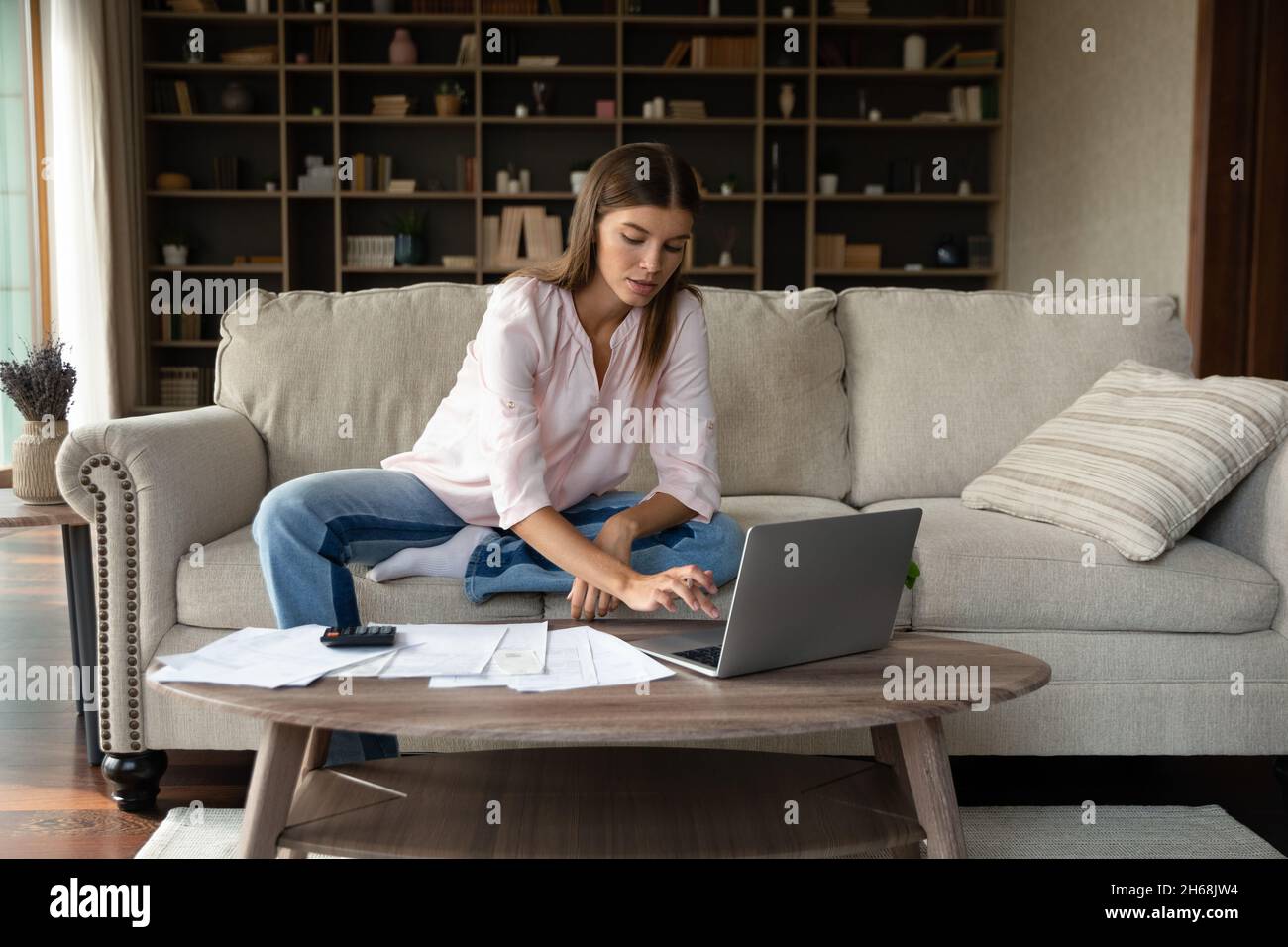 Concentrée jeune belle femme calculant le budget mensuel domestique. Banque D'Images