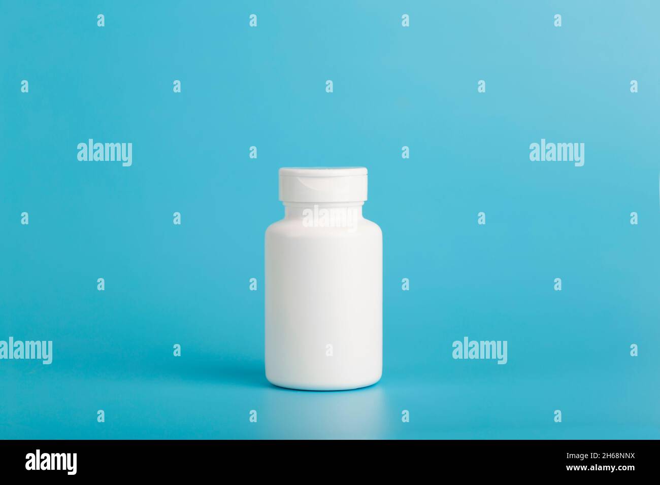 Pot de pilules isoler.Pot en plastique blanc pour les pilules médicales, les médicaments et les vitamines sur un fond blanc bleu.Photo de haute qualité Banque D'Images