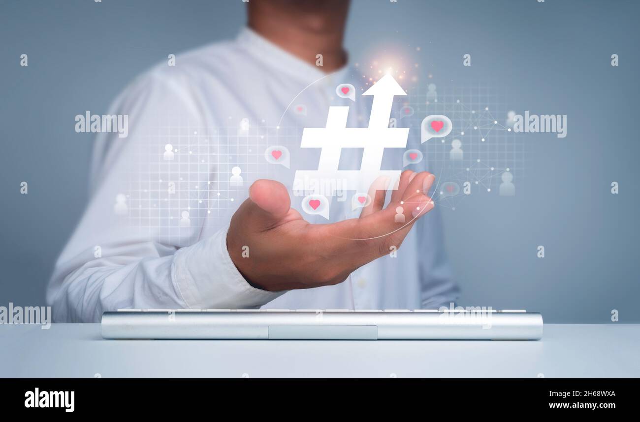 Concept hashtag.Icône hashtag avec flèche vers le haut dans la main de l' homme et symbole de personnes avec le coeur, l'amour dans les bulles de  parole flottant sur le réseau social web.Tr