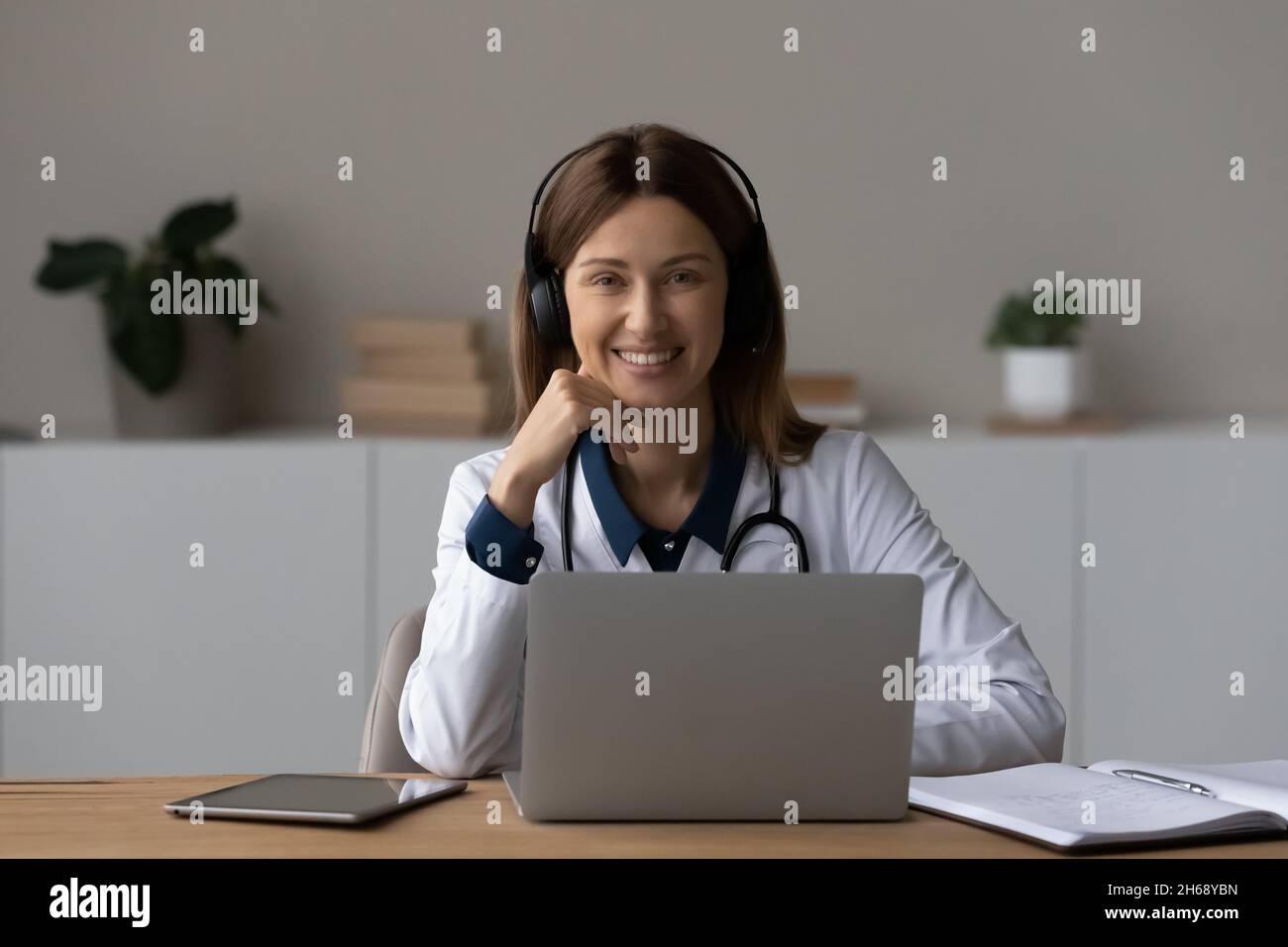 Portrait de la tête souriant femme médecin dans un casque à l'aide d'un ordinateur portable Banque D'Images