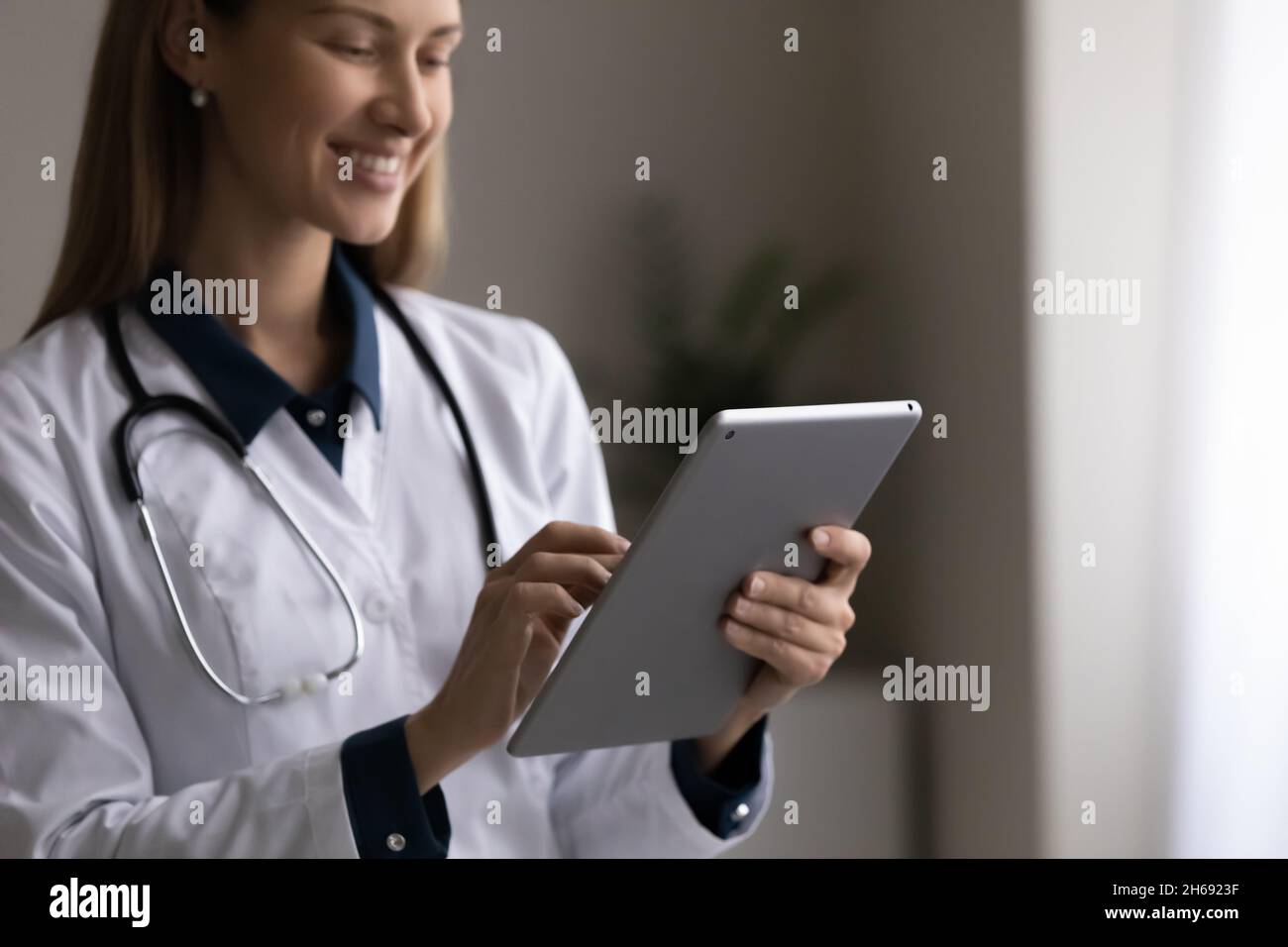 Gros plan sourire jeune femme médecin en uniforme à l'aide d'un comprimé Banque D'Images
