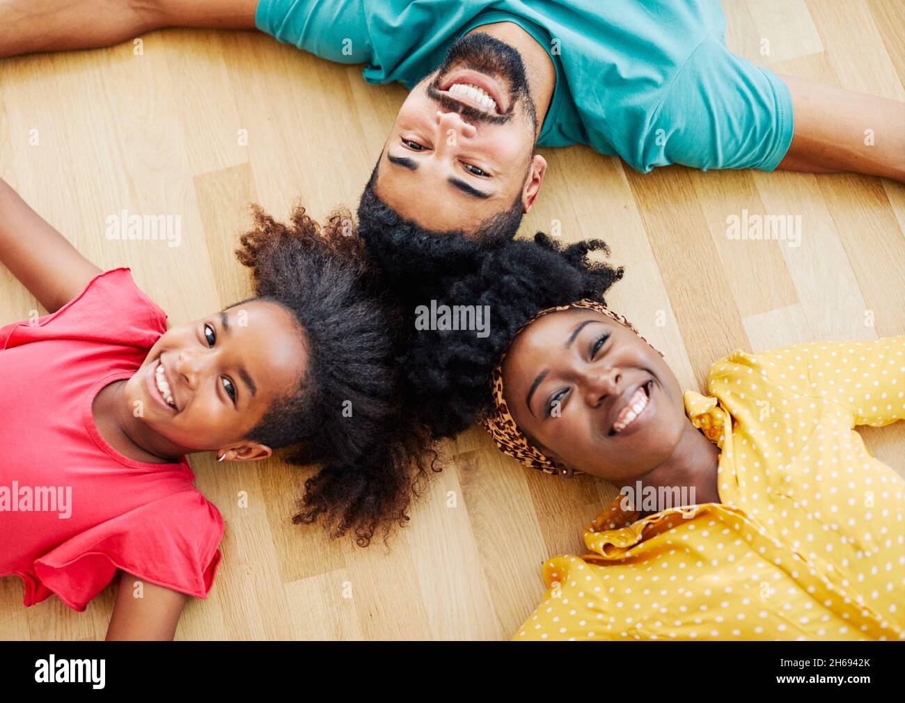 enfant fille famille heureuse mère père étage couché ensemble amusant fille gaie équipe équipe travail d'équipe maison noir Banque D'Images