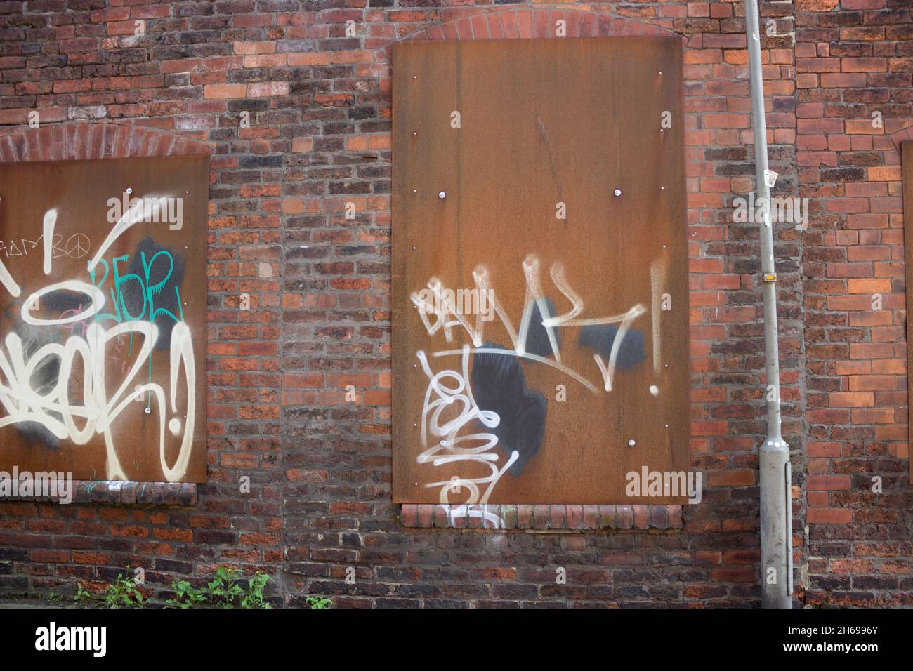 Bâtiment abandonné, abandonné, déserté, scellé, fenêtres en métal boarqué, zone urbaine de délabrage, extérieur en brique dans les ruines emplacement inoccupé Graffiti Banque D'Images